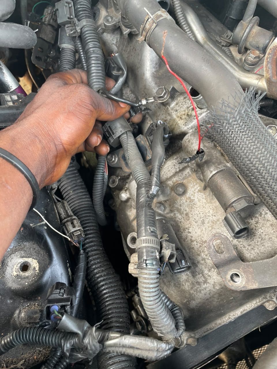 Mechanic tracing an engine wiring connector during a repair at Emmy Automobile Engineering
